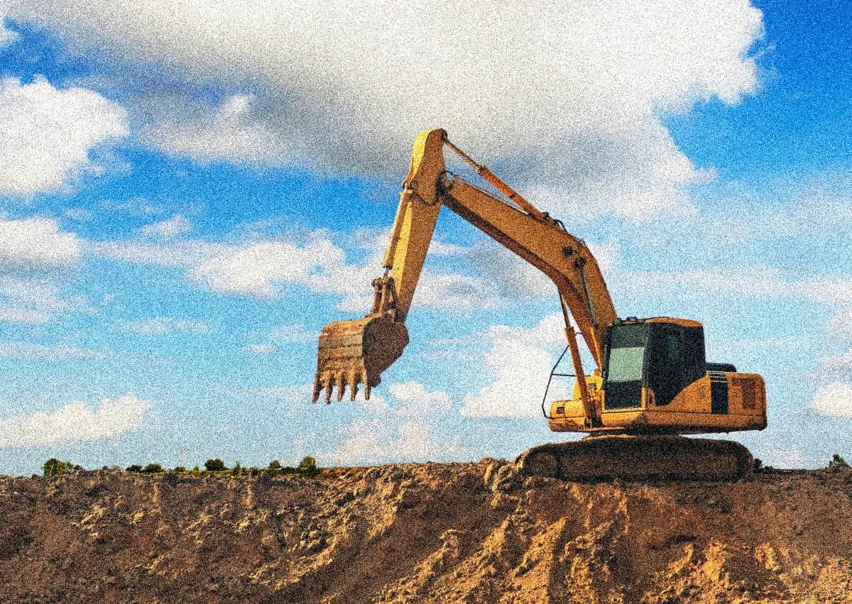 A yellow excavator digging earth in a construction side